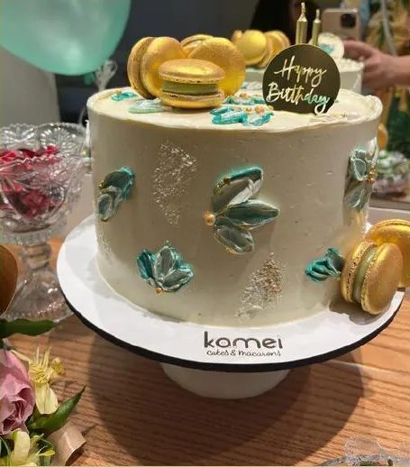 Bolo de buttercream com pinceladas verdes e macarons dourados