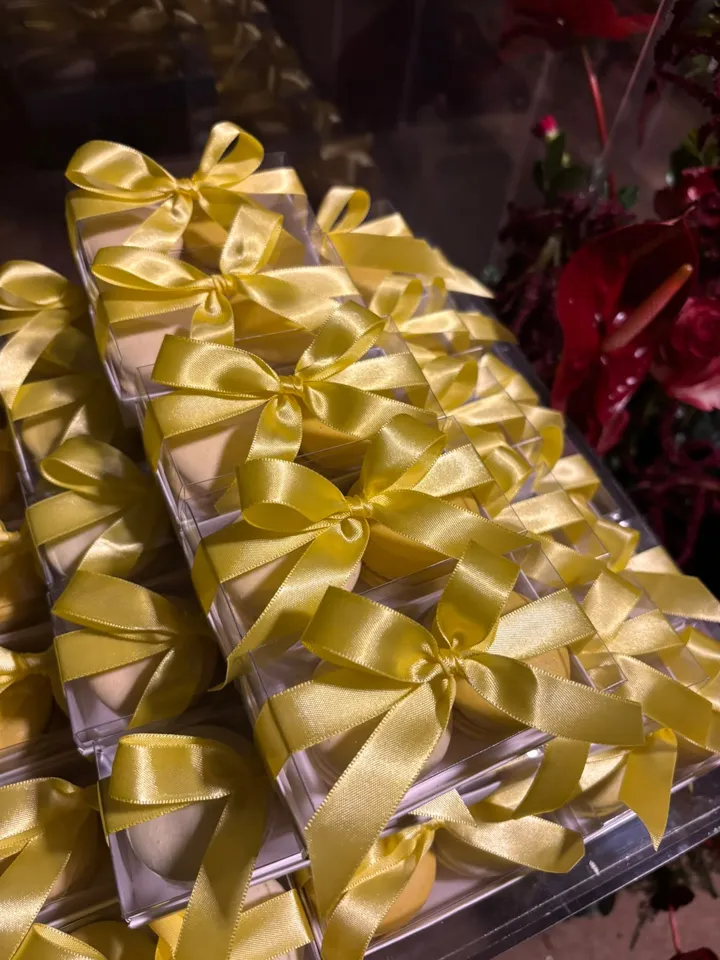 Caixinhas com macarons e laço de cetim amarelo em evento
