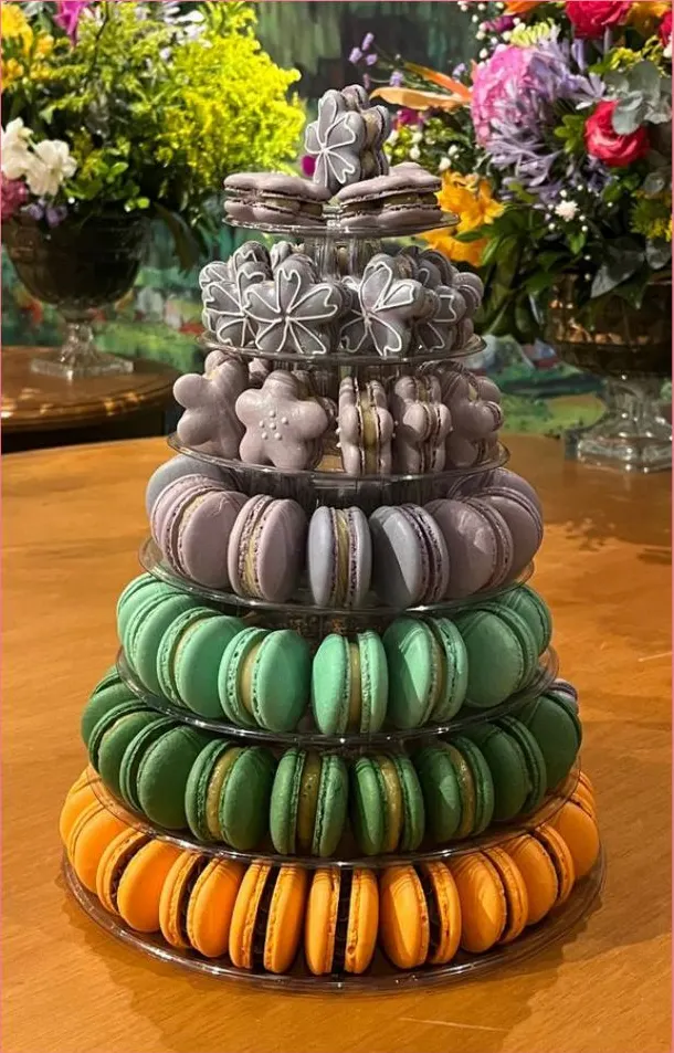 Torre de macarons laranja, verde e lilás com flores